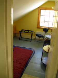 The 4th and smallest bedroom in our house is under the eaves on the 2nd floor.  It has 2 single futons set on a quilt, and also has a luggage rack, small tables, lots of pillows & blankets, a floor lamp, small tables, and a nice west-facing casement window, for good light and breezes.  And along with the wide pine floorboards, another great 200 year old hand-planed door.