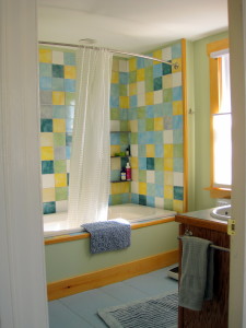 The first floor has a large bathroom with oversized tiled bathtub, large counter & mirror, plenty of towels, and windows looking east (on right) and north, looking out onto the back yard (not shown). Original wood floor with wide pine boards.